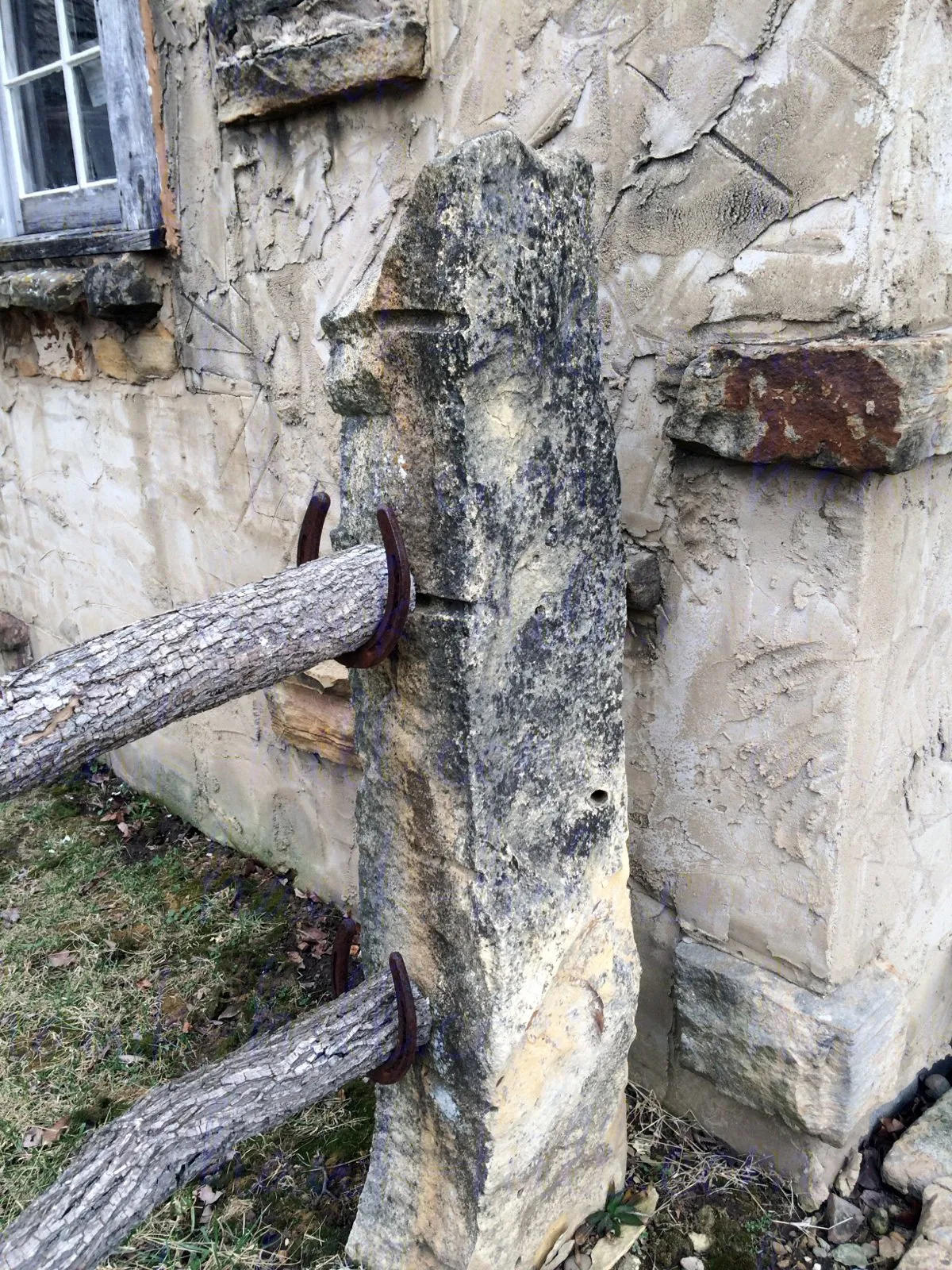 Stone fence post with horseshoe rail bracket.