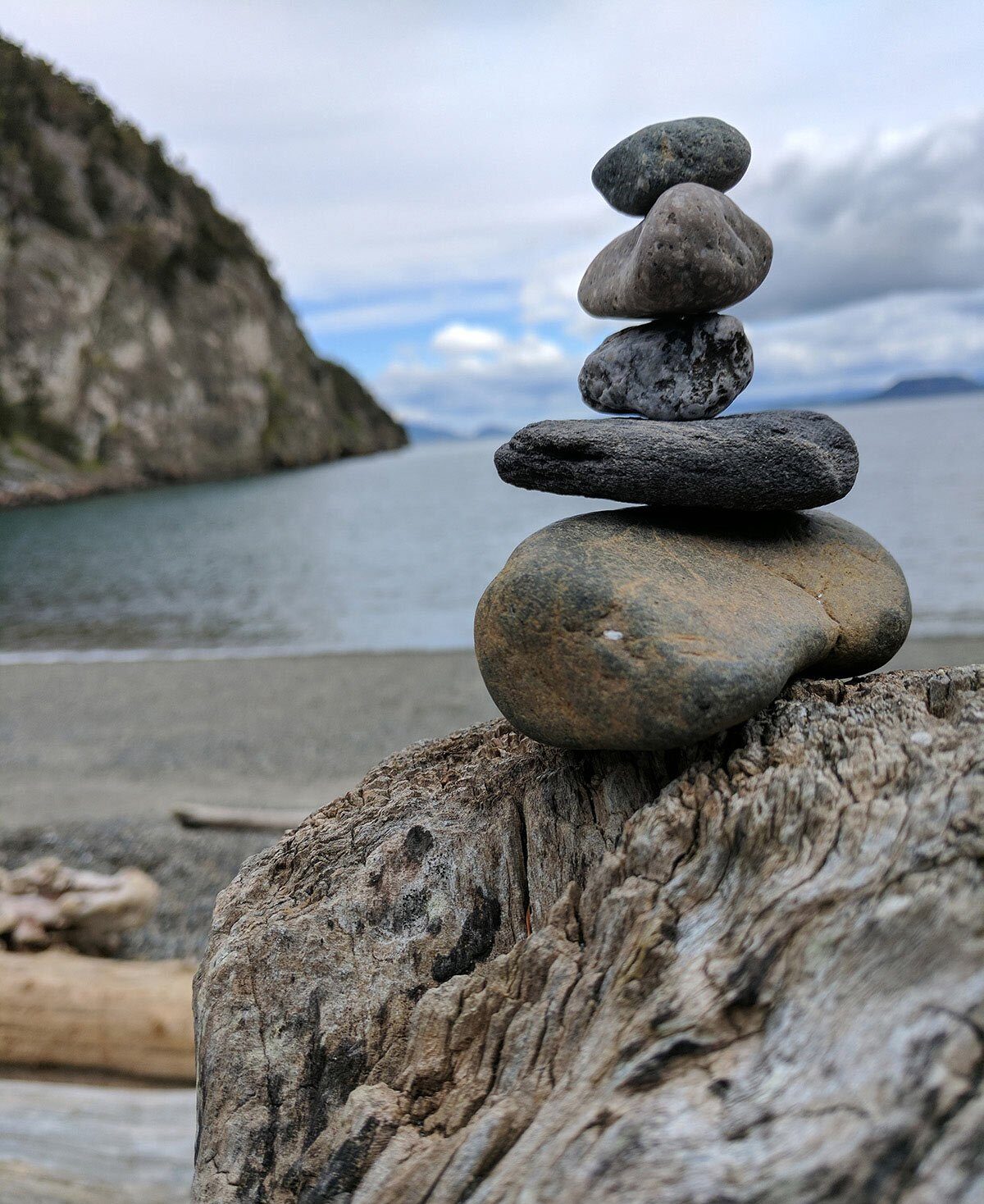 Stacked rocks on driftwood on a pnw beach.