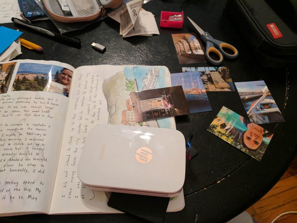 A portable printer printing photos for a travel scrapbook.