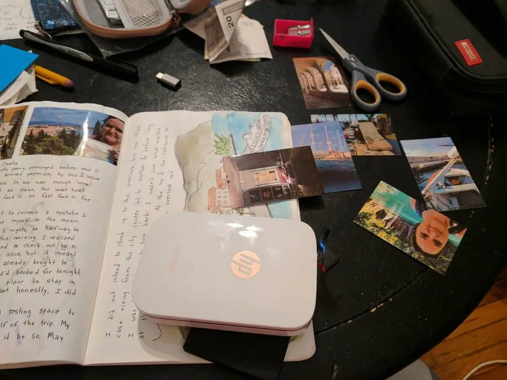 A portable printer printing photos for a travel scrapbook.
