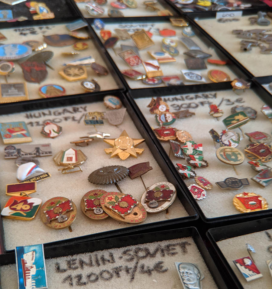 Cases full of decorative lapel pins for sale at a flea market in a ruin bar in budapest romania