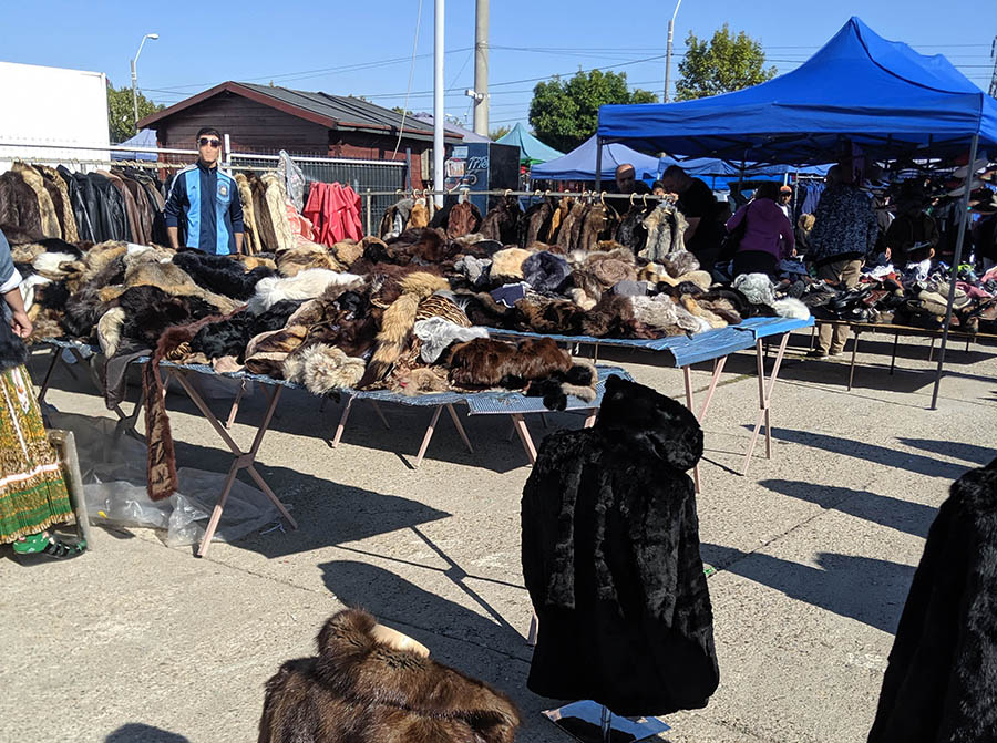 A booth full of used fur coats at an outdoor flea market in bucharest romania
