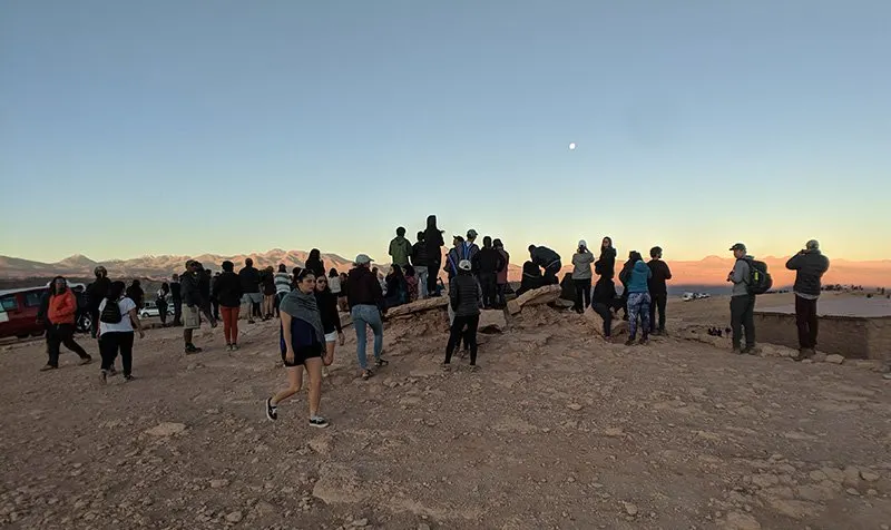 A group of travelers crowds a scenic overlook in the atacama desert.