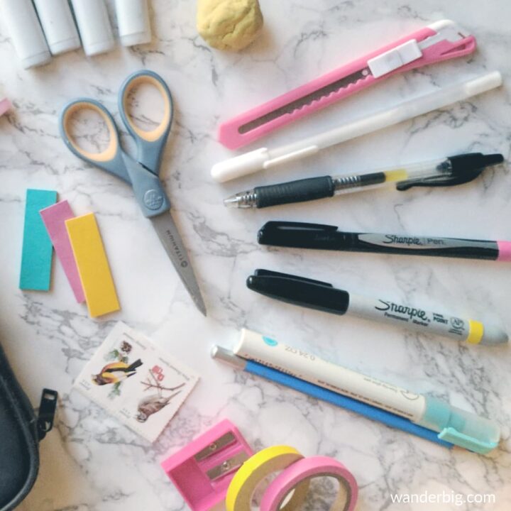 Pens, scissors, and other bullet journal supplies spread out on a table.