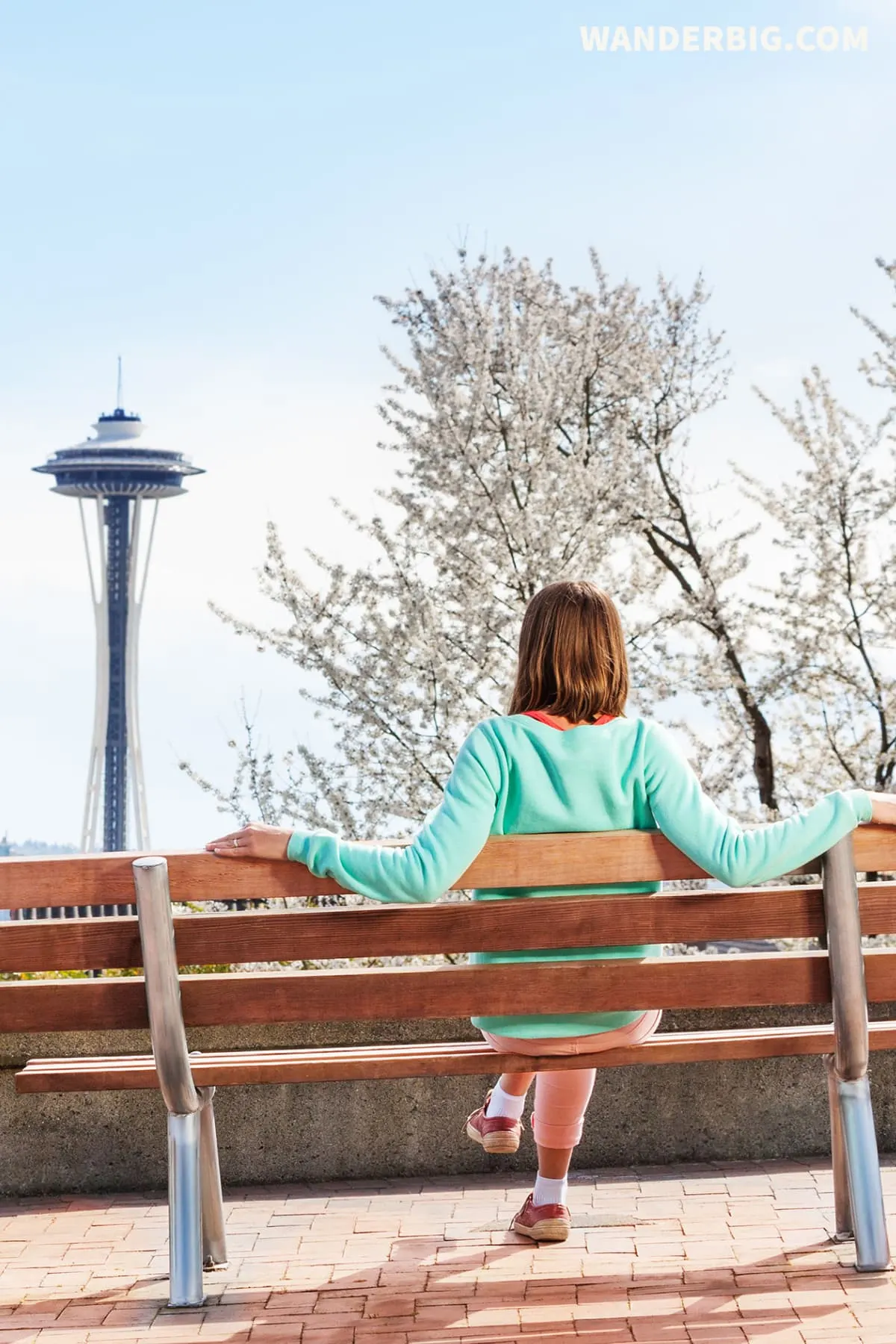 A woman sits on a bench in kerry park in seattle, enjoying a solo travel visit.