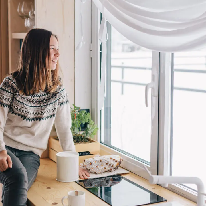 Woman looking out window in kitchen.