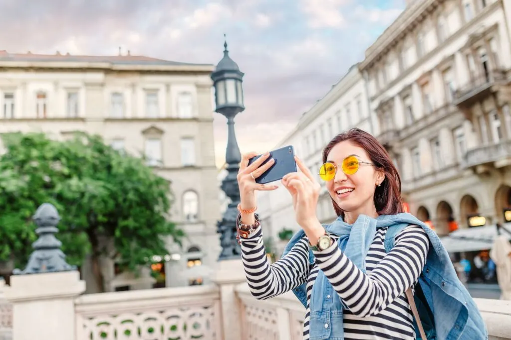 A woman takes a selfie photo in an urban backdrop.