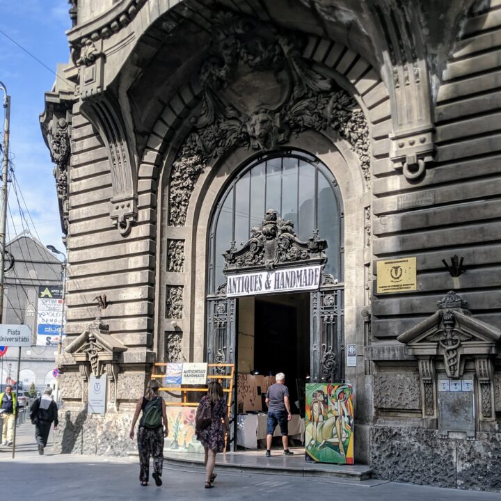 People walking into an old building with a sign that says antiques and handmade