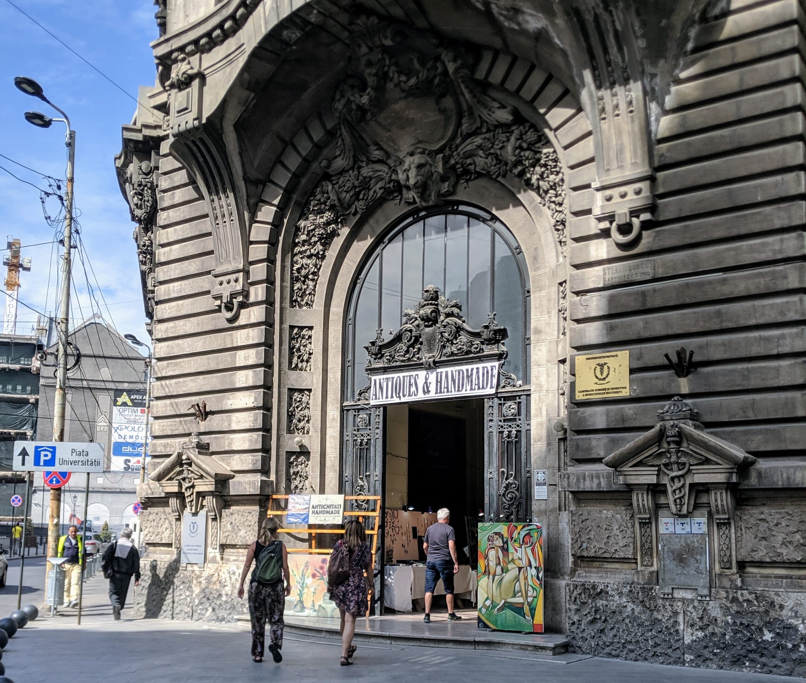 People walking into an old building with a sign that says antiques and handmade, where the purchase of handmade goods can be part of sustainable travel.