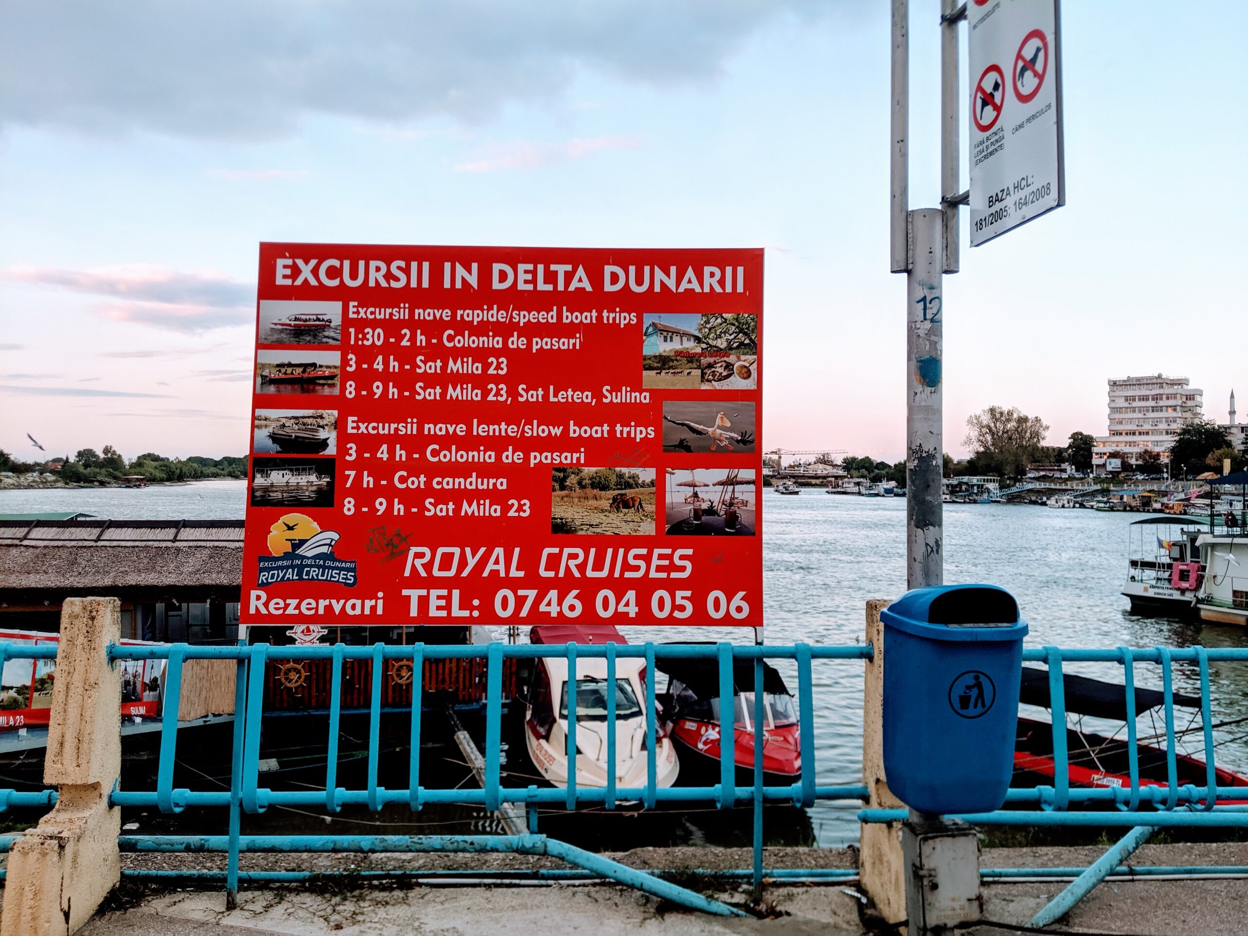 Red sign advertising tour prices hanging on a harbor wall.