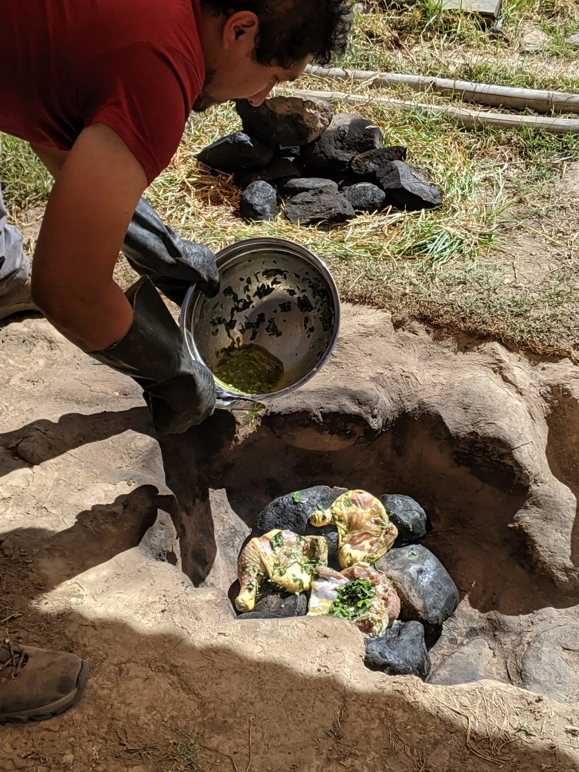 A man places chicken breasts into an oven that have been marinated in a mixture of andean herbs.
