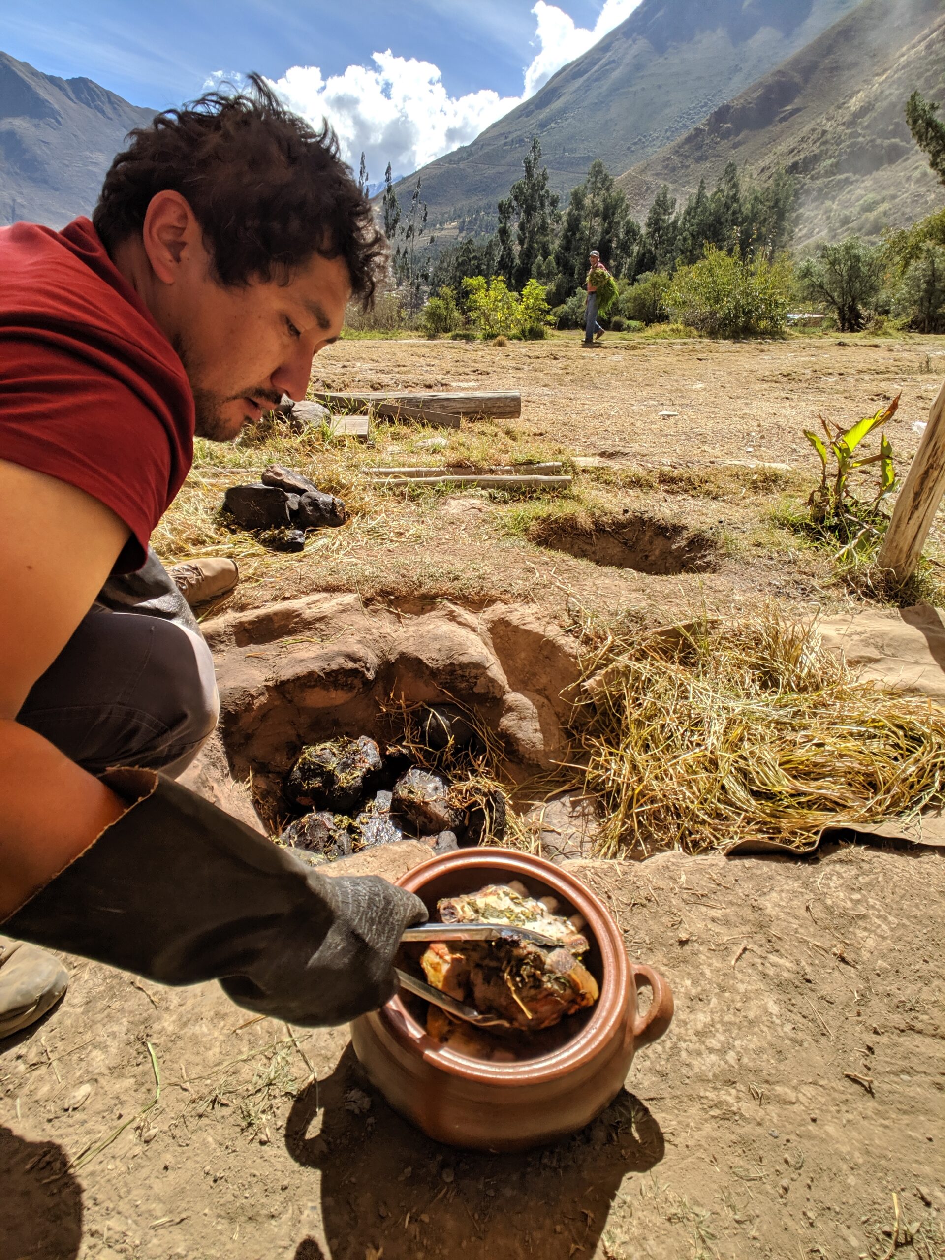 A man pulls meat from a clay oven in peru, photo taken with consent.