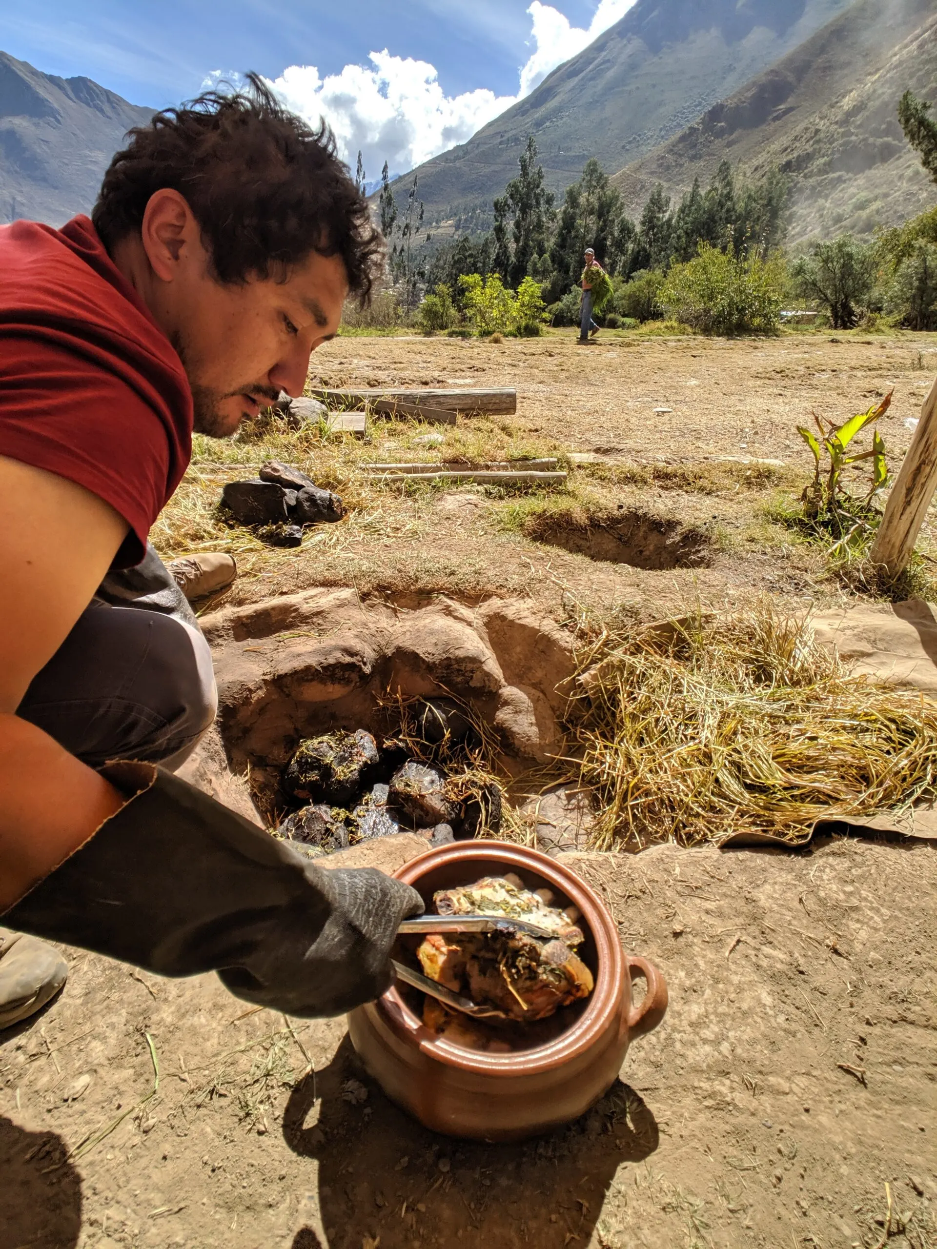 A man pulls meat from a clay oven in peru, photo taken with consent.
