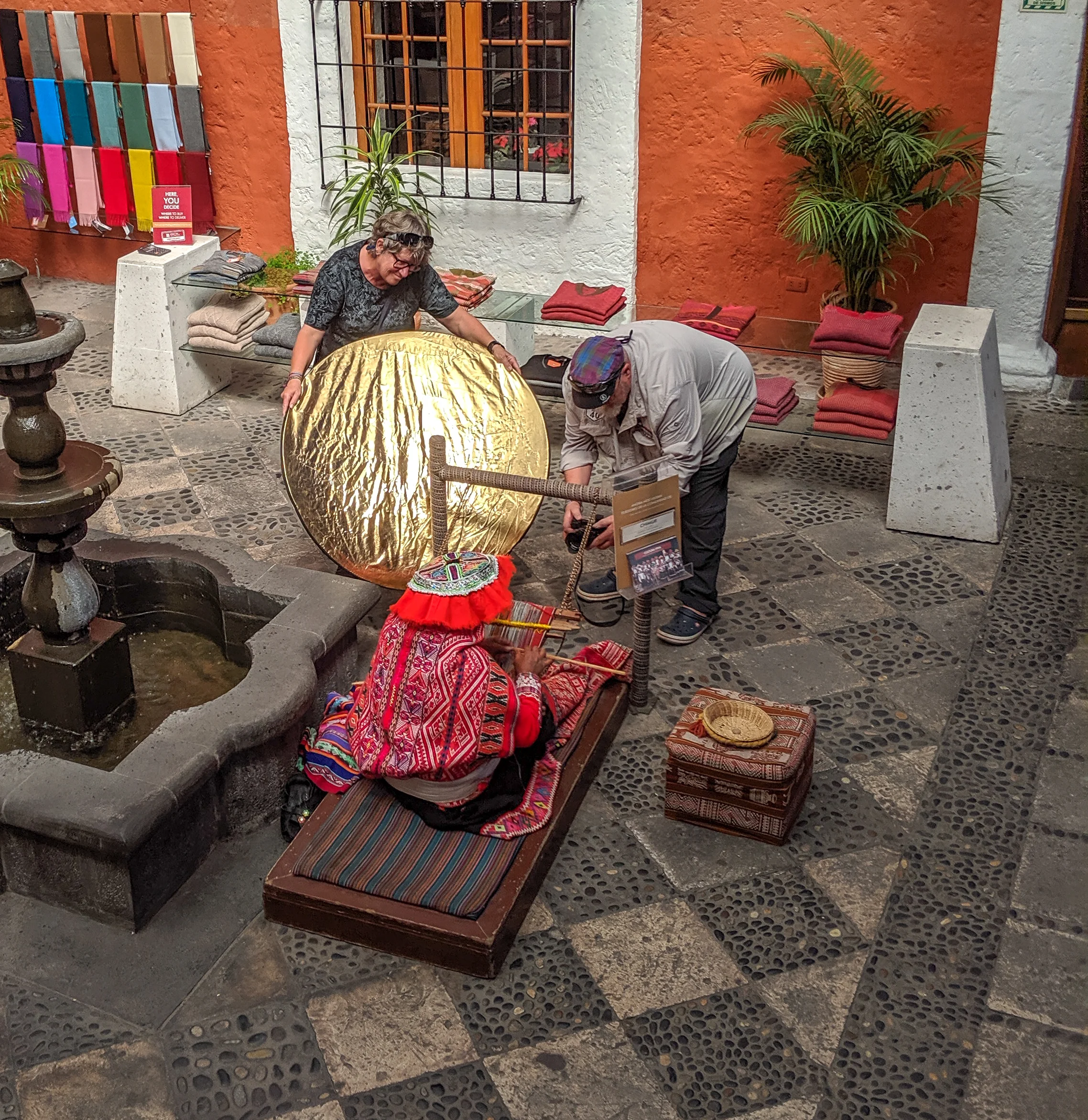 Two western tourists use professional equipment to photograph an indigenous woman in peru.