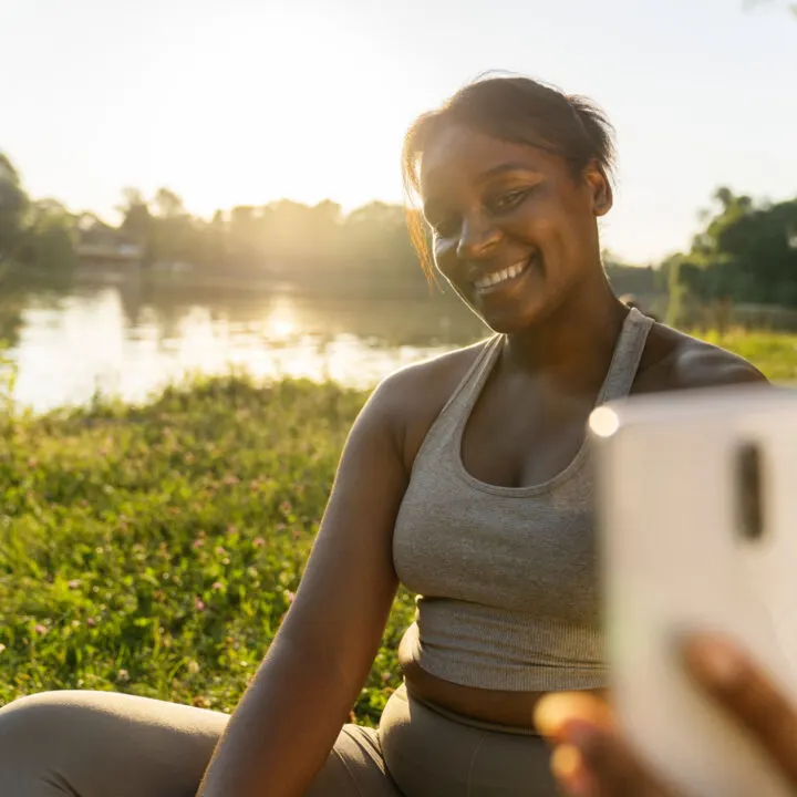 a woman sitting in front of a lake taking a travel influencer style selfie