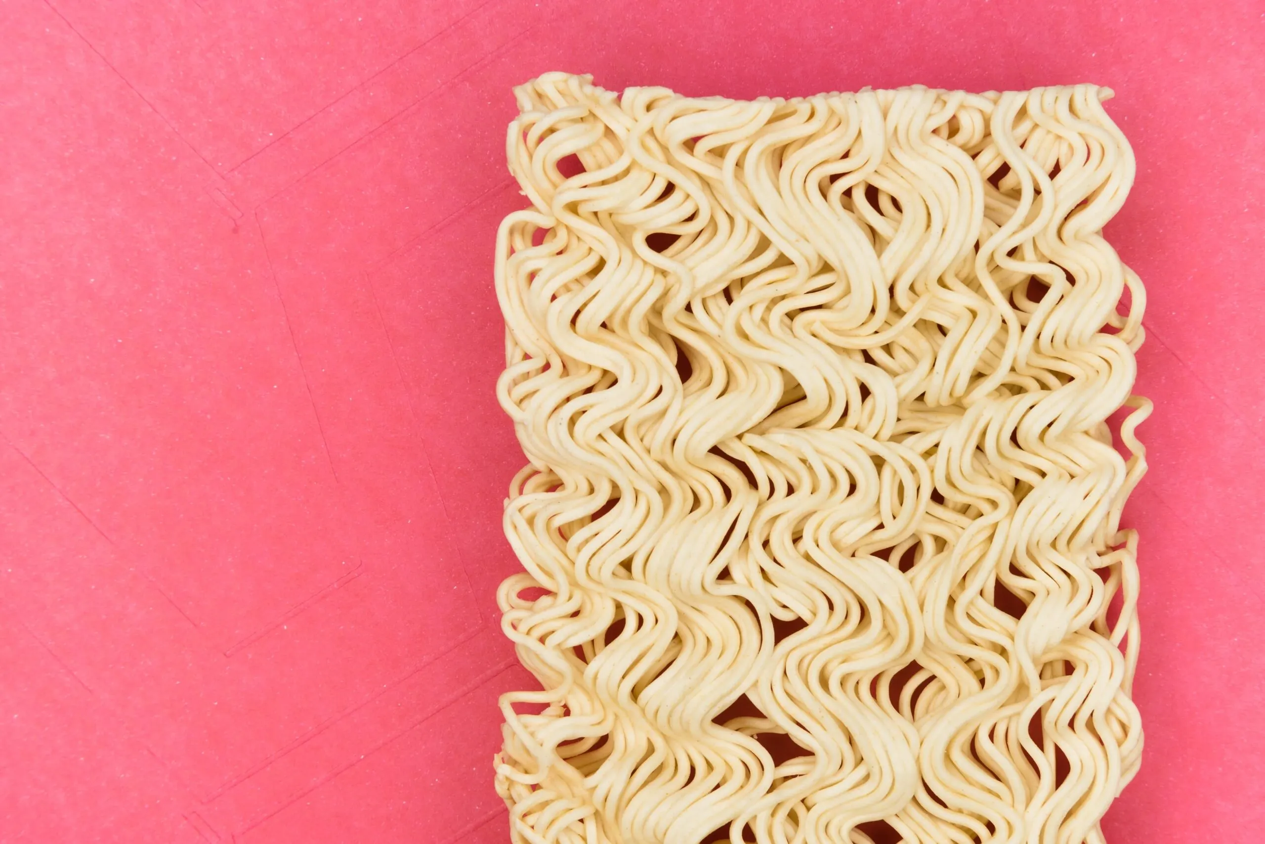 Ramen noodles on a pink background.