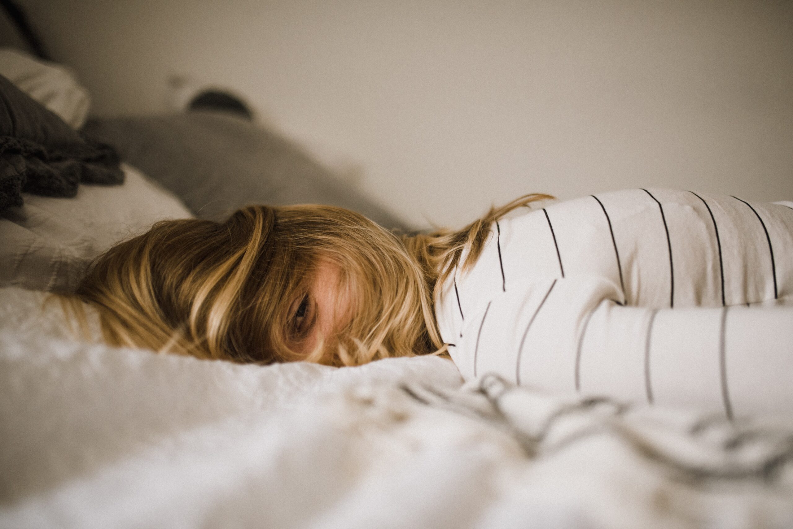 A woman lays face down on a bed, potentially experiencing jet lag as her body adjusts to  new time zone.
