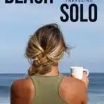 A woman stands on the beach with a drink