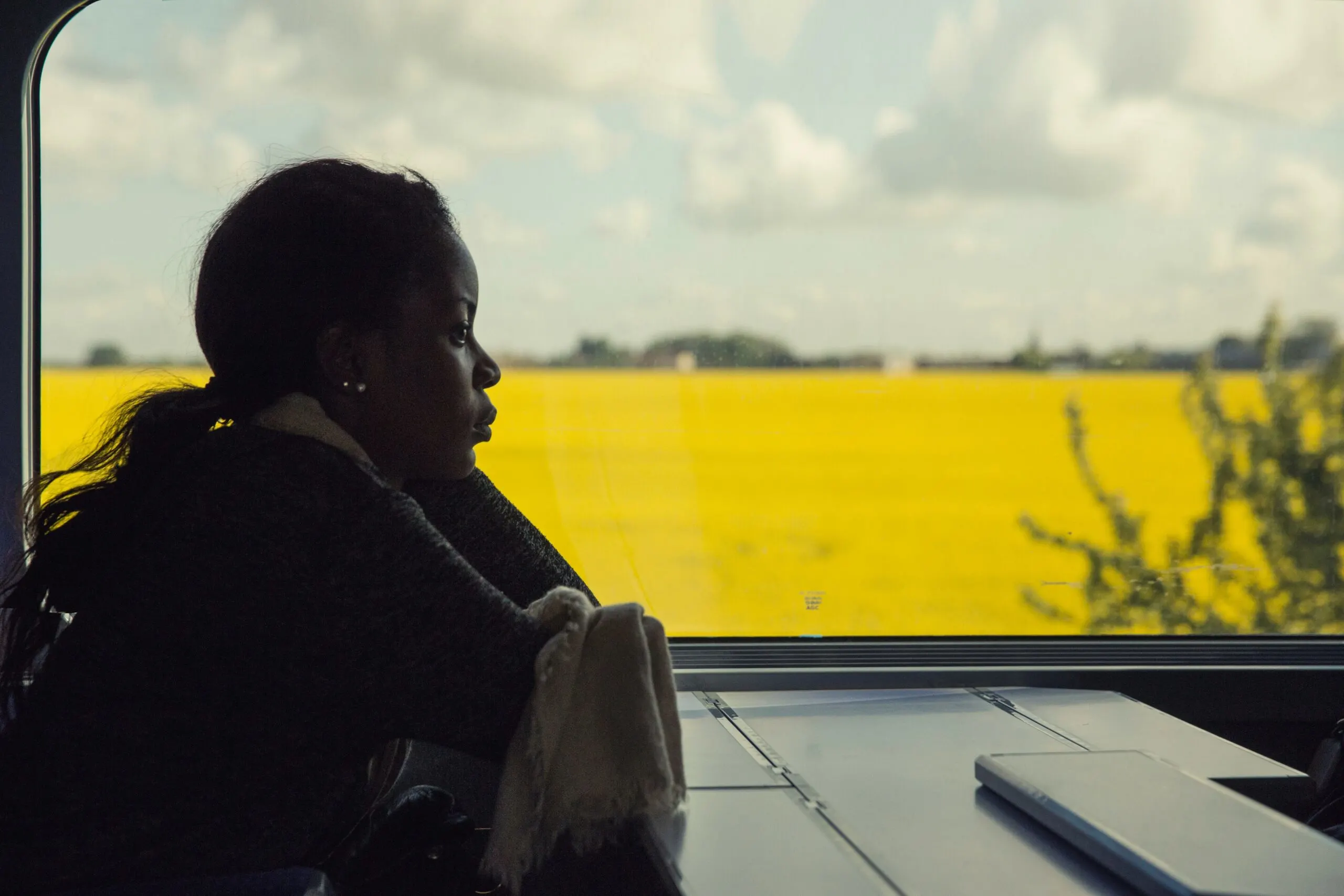 A woman sits on a train and stares into space.