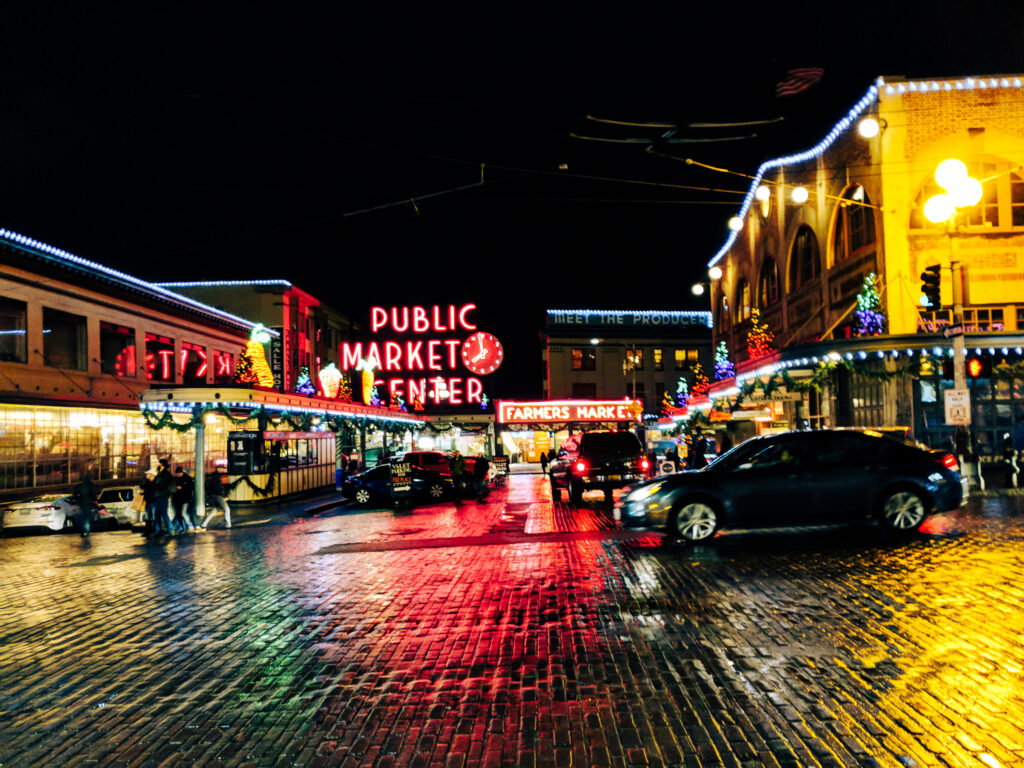 Pike place market at christmas after dark, with car driving past.