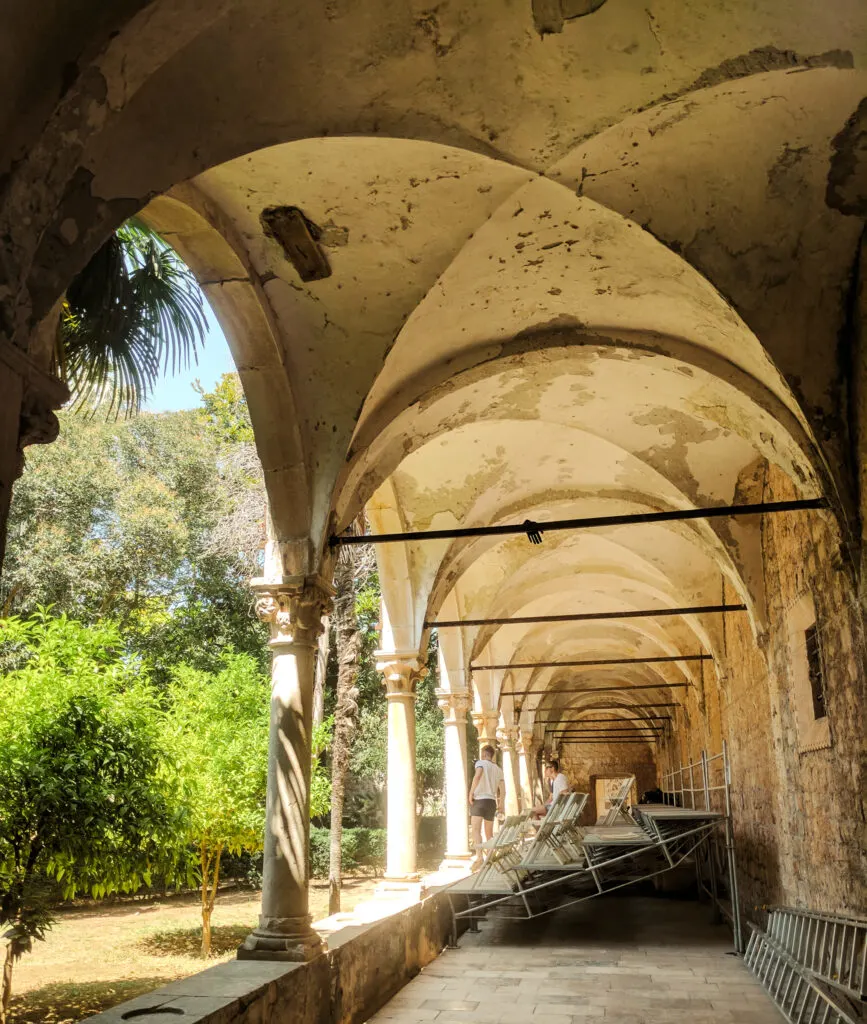 Arches of a monastery surrounding a courtyard with an orchard.