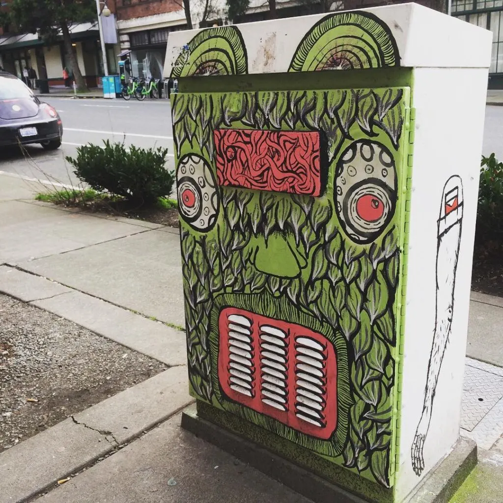 This painted utility box, depicting a green mythical creature, is one of a number of smaller street murals in seattle.