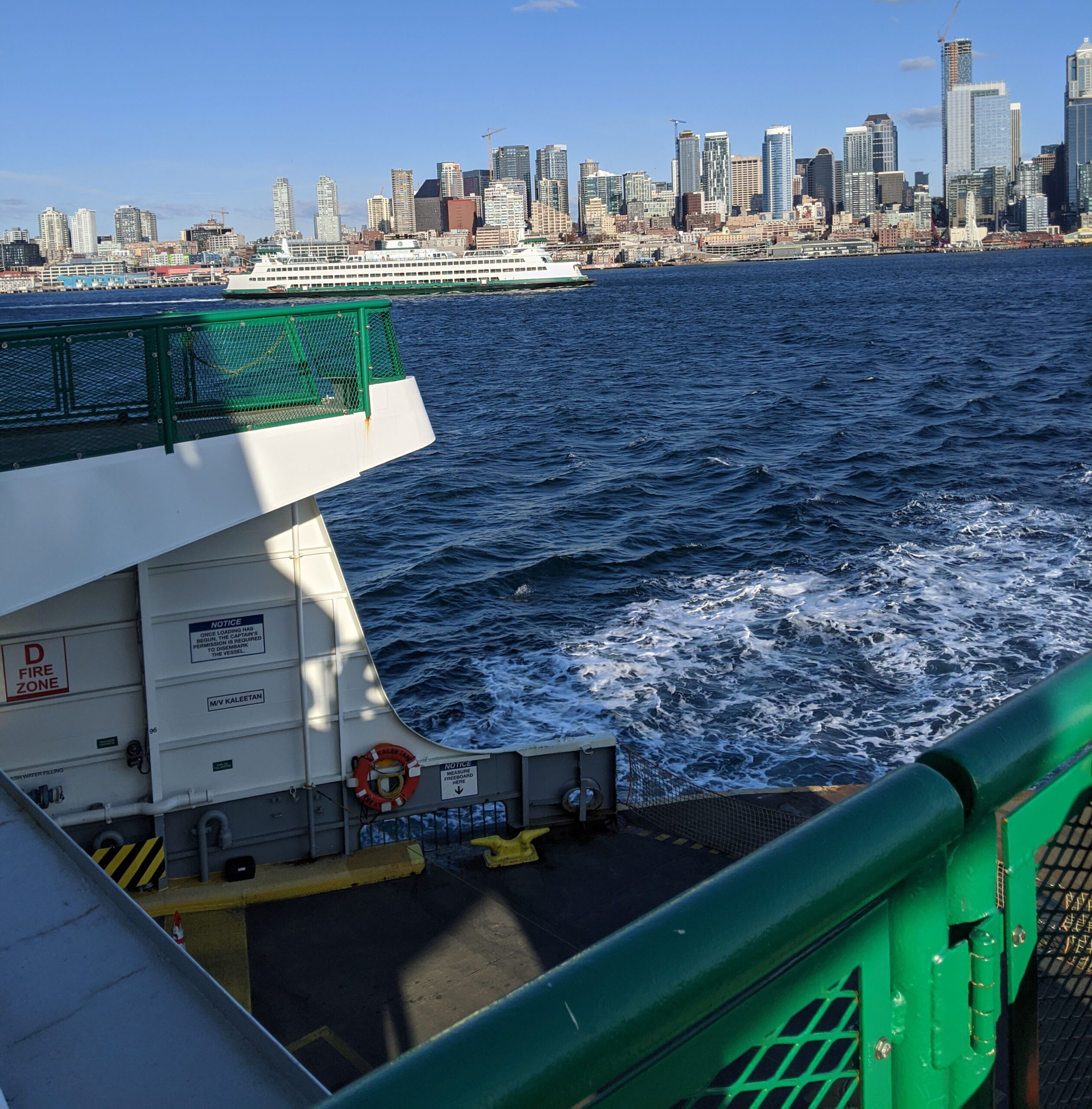 Washington state ferry leaving seattle bound for bainbridge island, with the seattle skyline in the background.