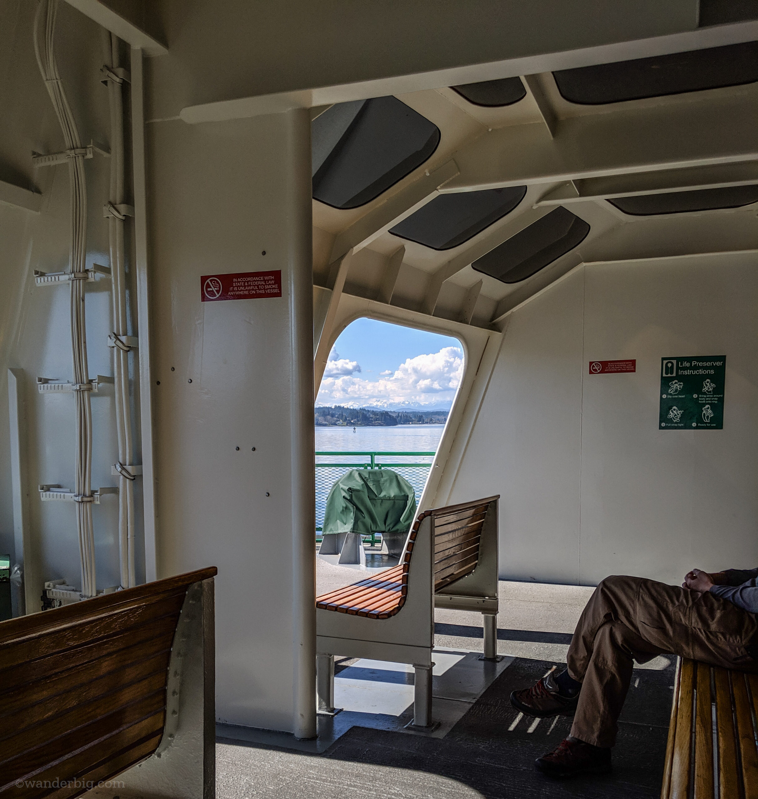Wood seats at the front of the passenger deck on a washington state ferry provide a great view with some shelter from the weather.