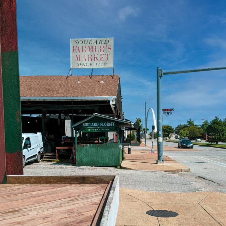 Soulard Market in Saint Louis, Missouri, with gateway arch in backdrop.