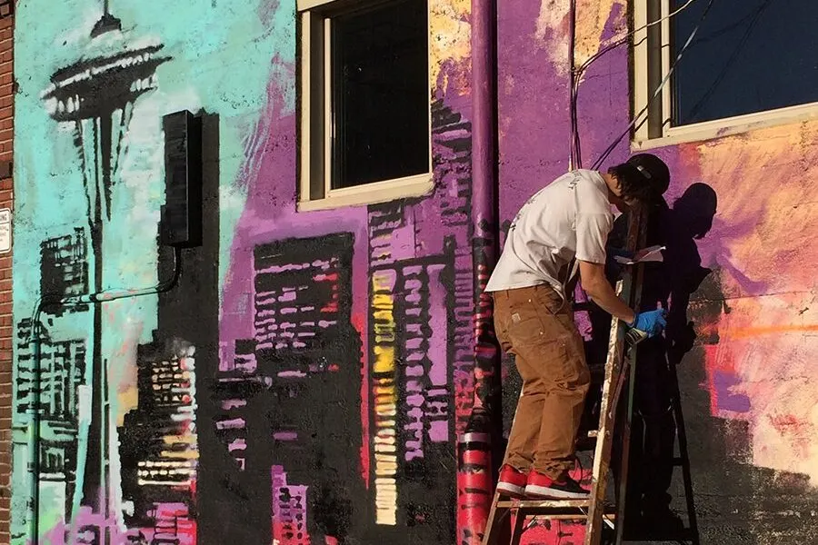 A man painting a mural of seattle