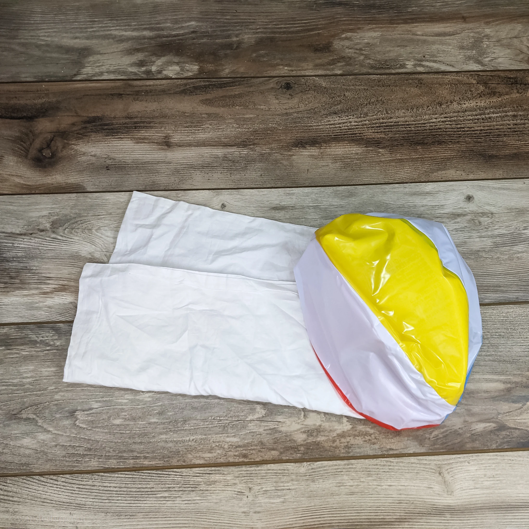 This image shows the two items you'll need to make a diy travel pillow: a zippered pillowcase and a uninflated beach ball.