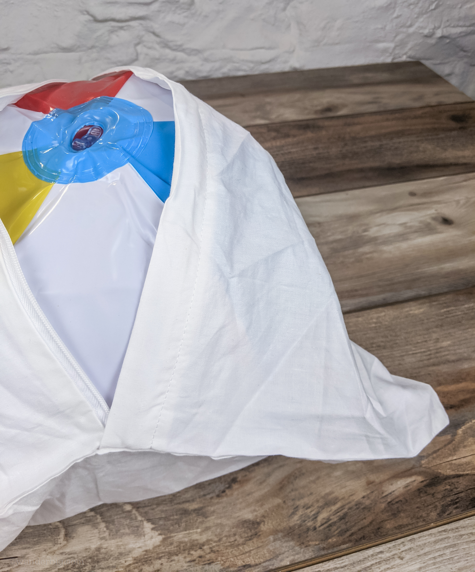A pillowcase partially zipped over a beach ball.