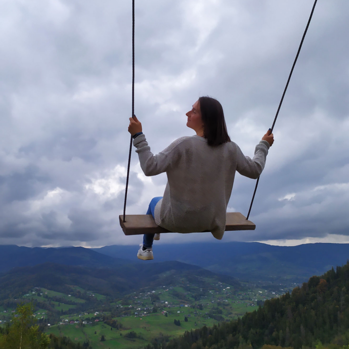 Woman on a swing with a travel landscape in the background.