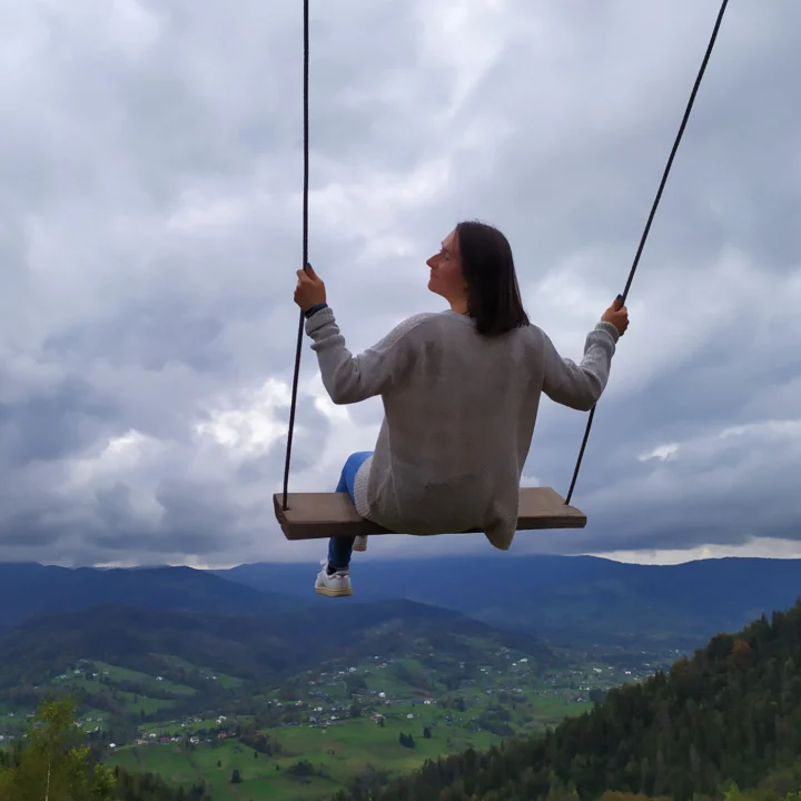 Woman on a swing with a travel landscape in the background.