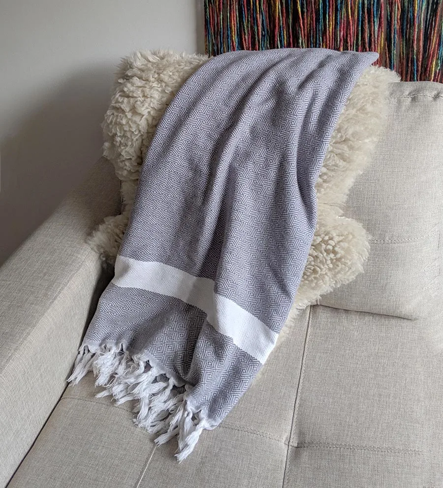 A cotton turkish towel draped on a sofa in chile.