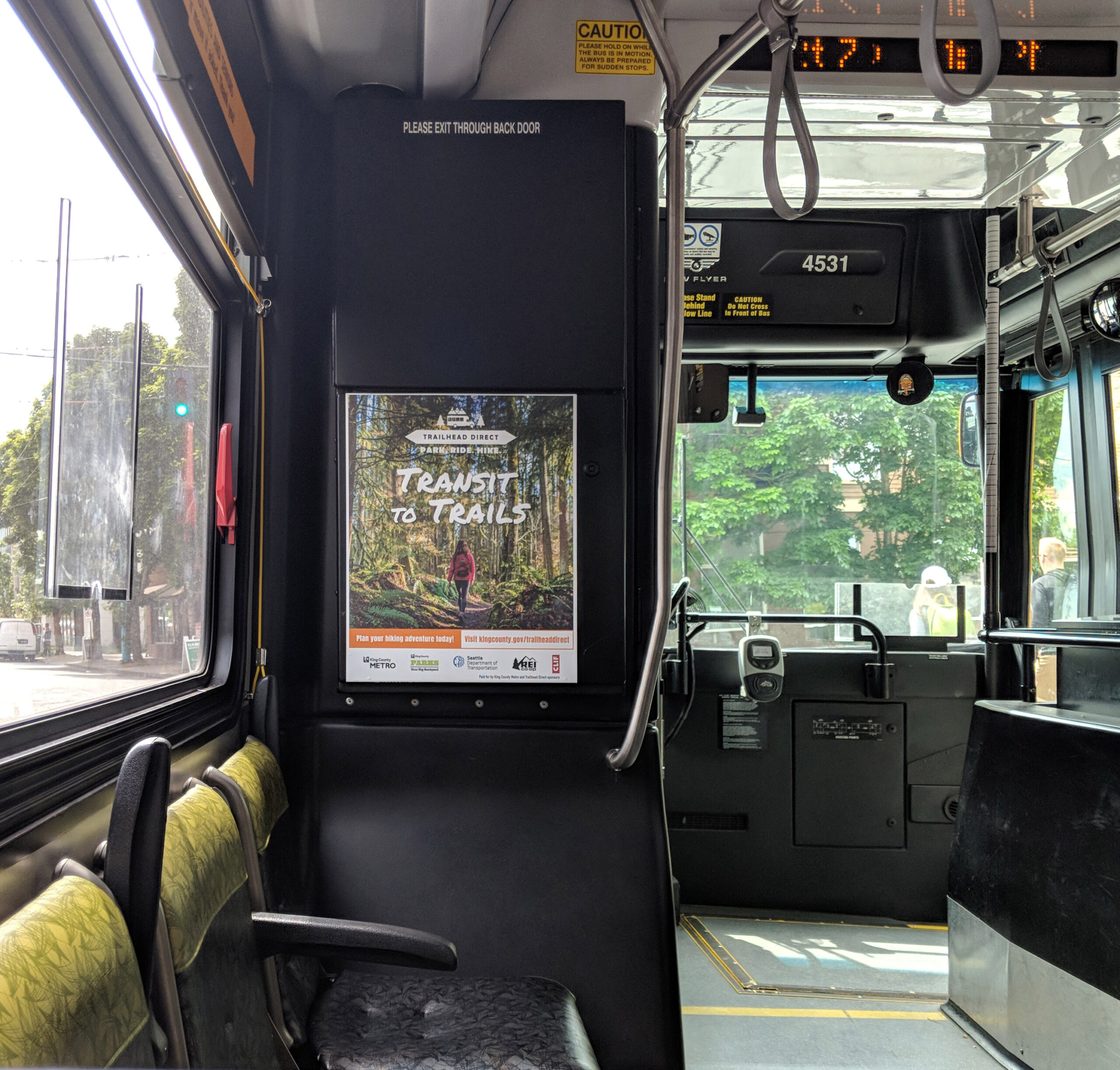 A public bus in seattle displaying a transit to trails poster.