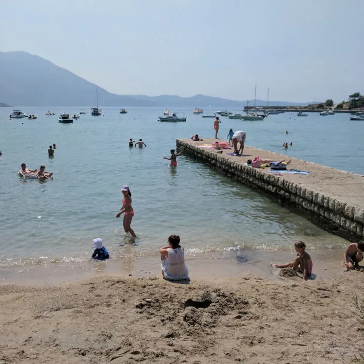Families playing in the surf on a beach and dock in Croatia.