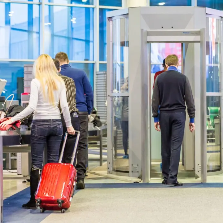 Travelers passing through a security checkpoint in an airport.
