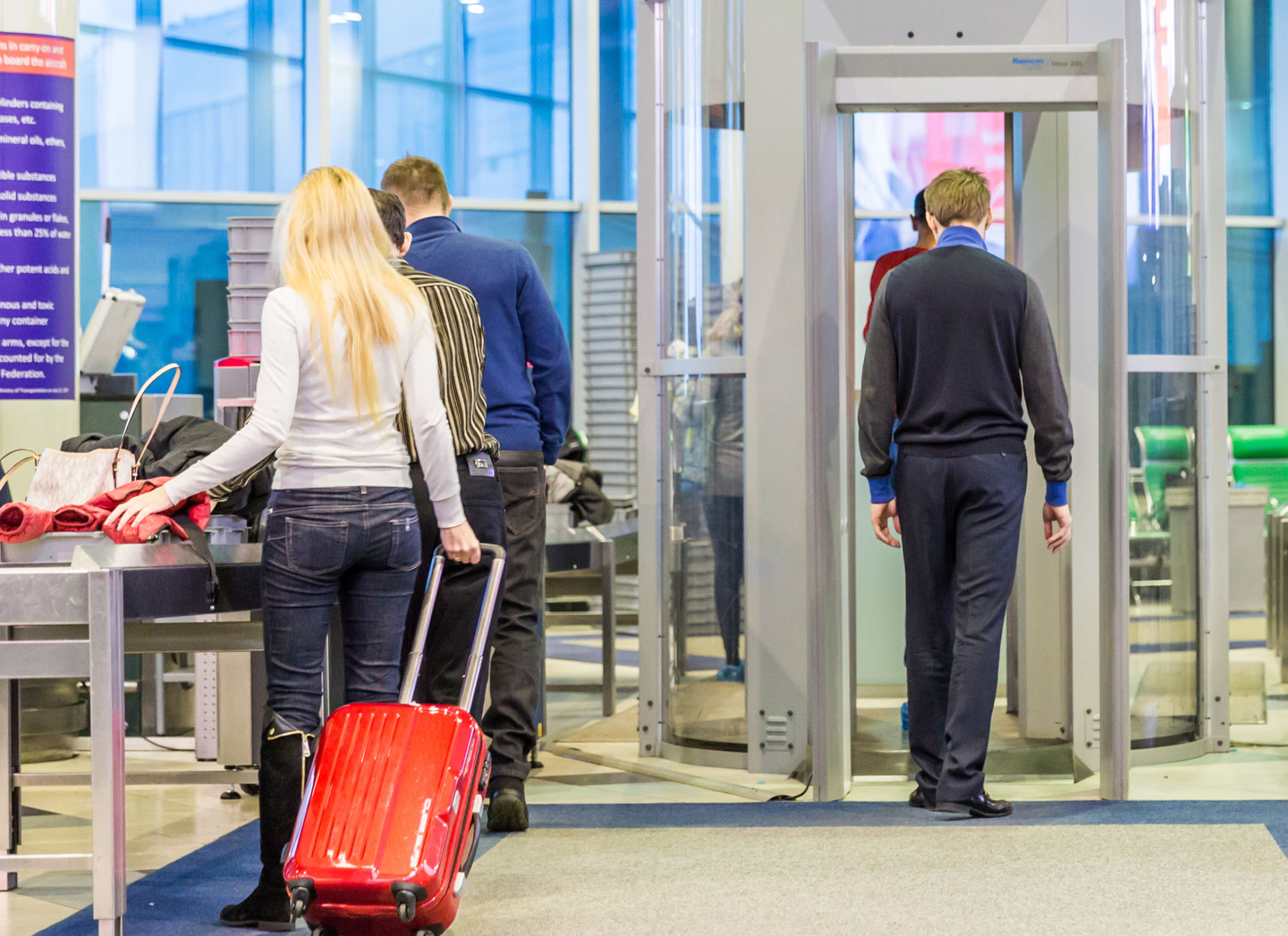 Travelers passing through a security checkpoint in an airport.