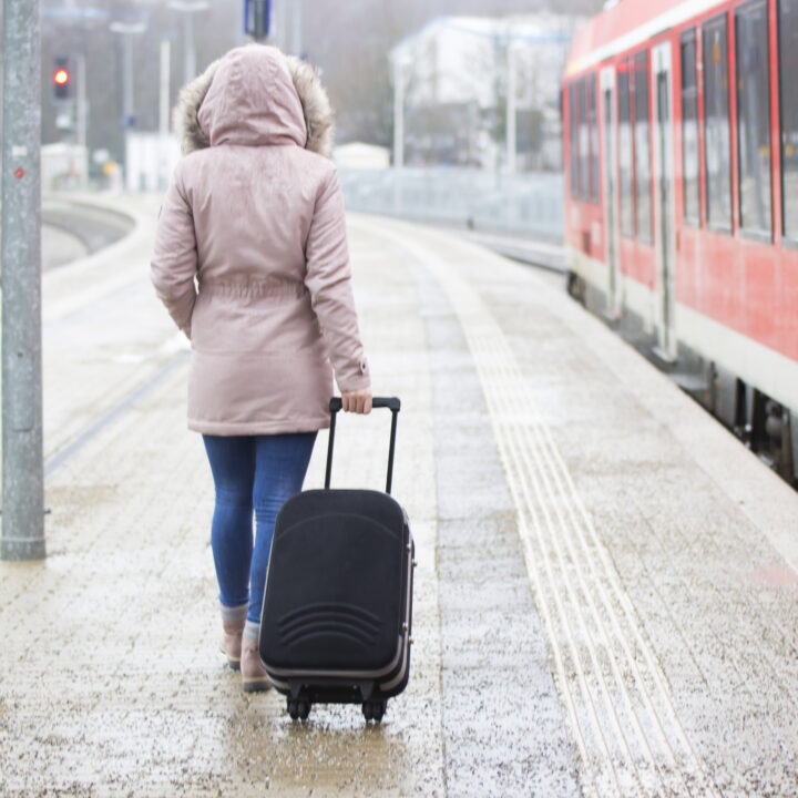 Woman rolls luggage in a wintery train station platform.
