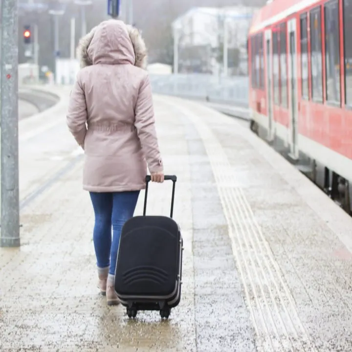Woman rolls luggage in a wintery train station platform.