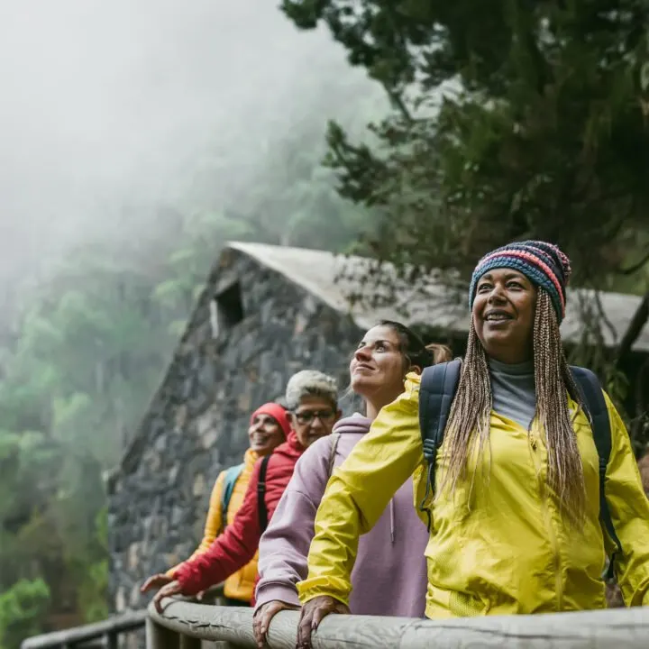 A group of women travelers walk along a foggy path.