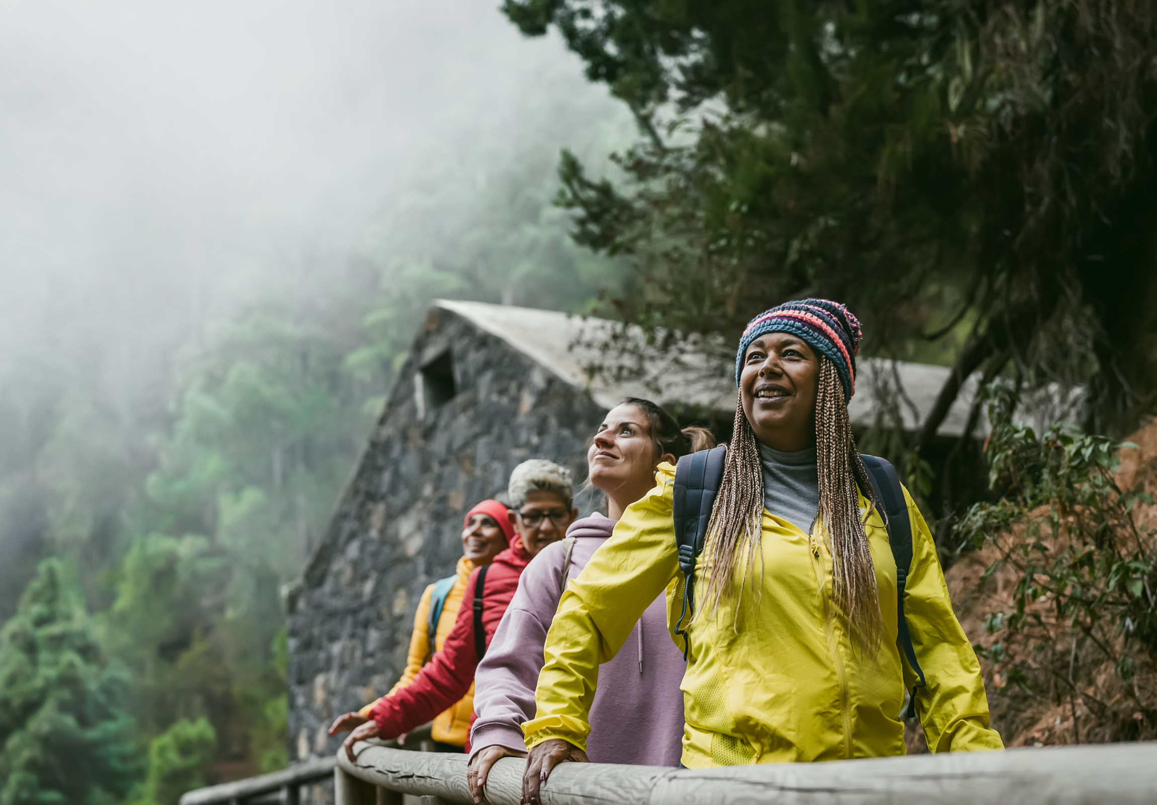 A group of women travelers walk along a foggy path.