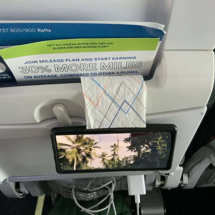 A cell phone mounted on the back of an airline seat for easy viewing.