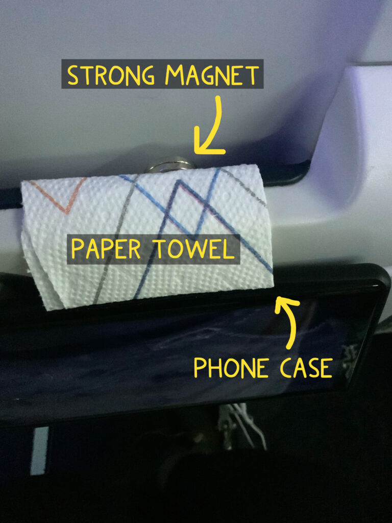 A cell phone mounted on the tray table on back of an airline seat for easy viewing.