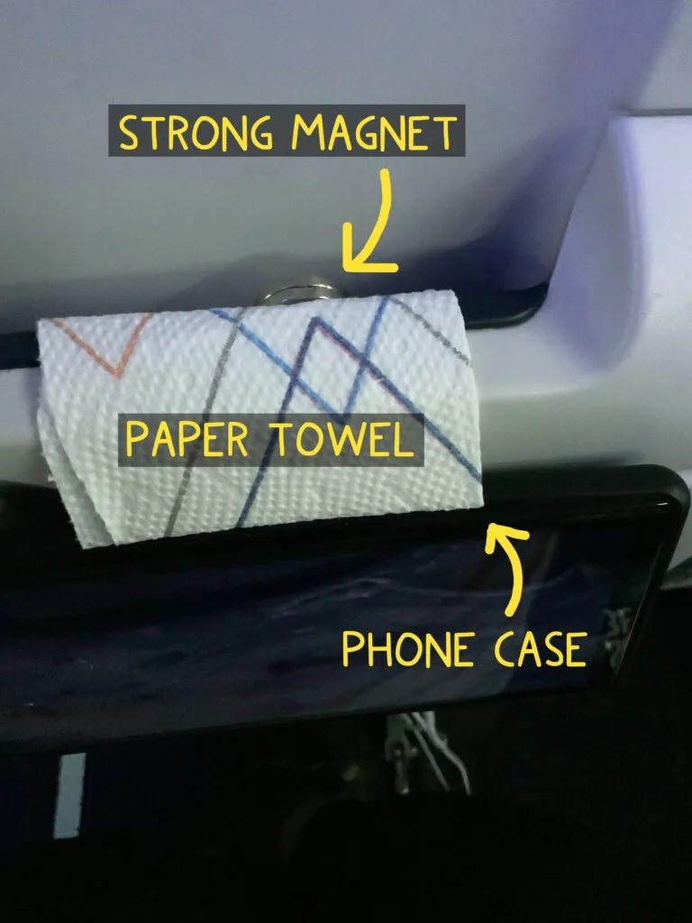 A cell phone mounted on the tray table on back of an airline seat for easy viewing.
