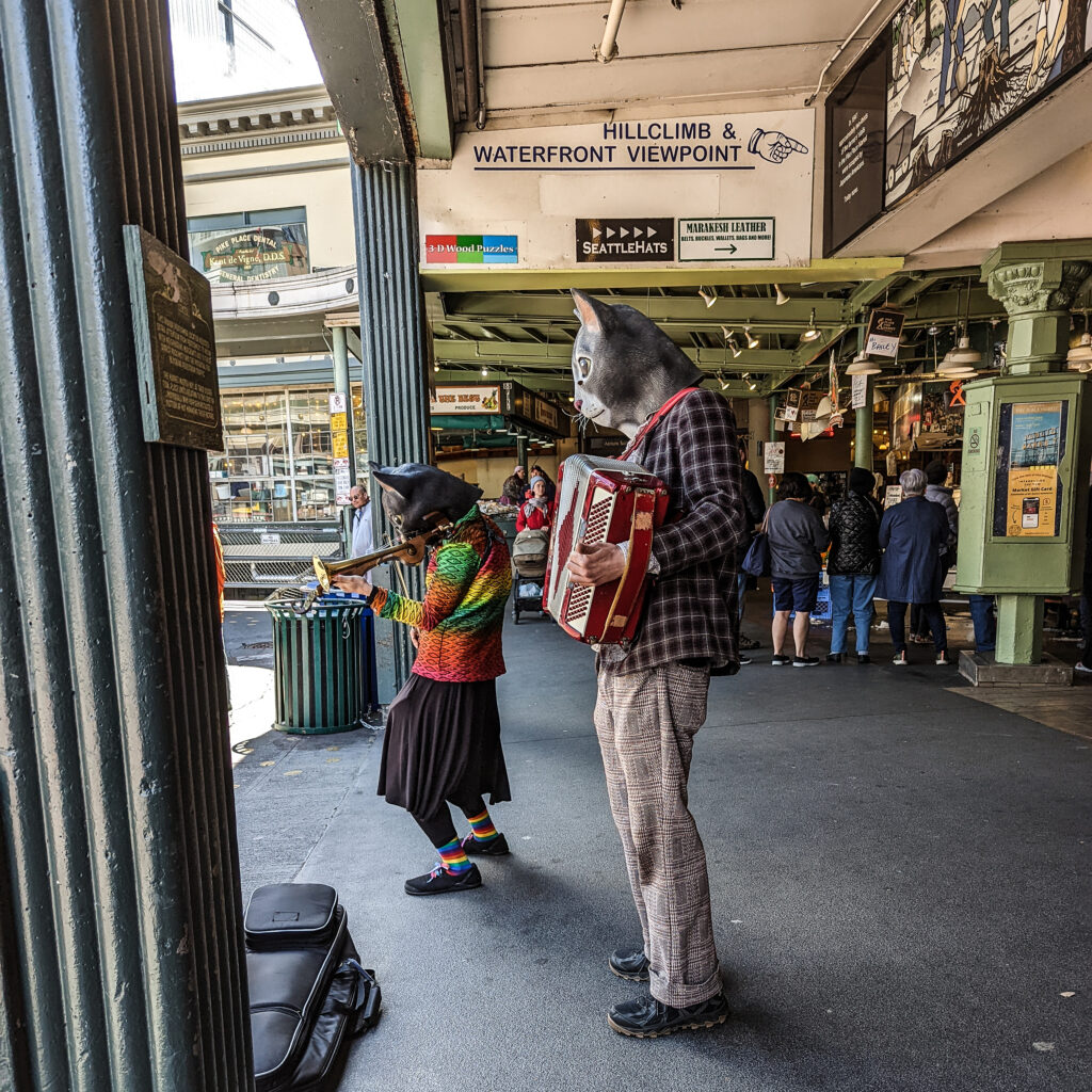 Buskers with cat masks play at pike place market.