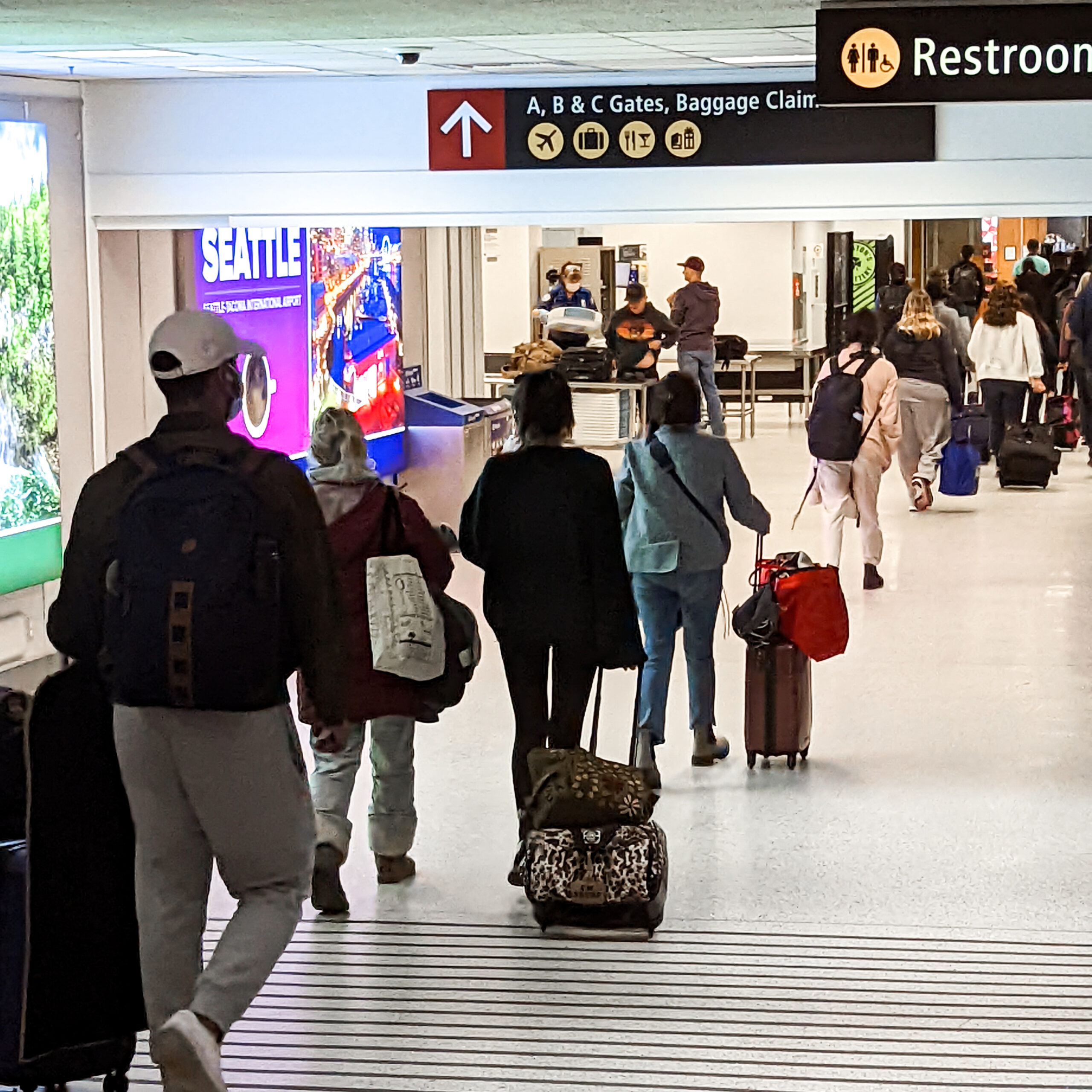 Passengers walking through a terminal at seatac headed to baggage claim.