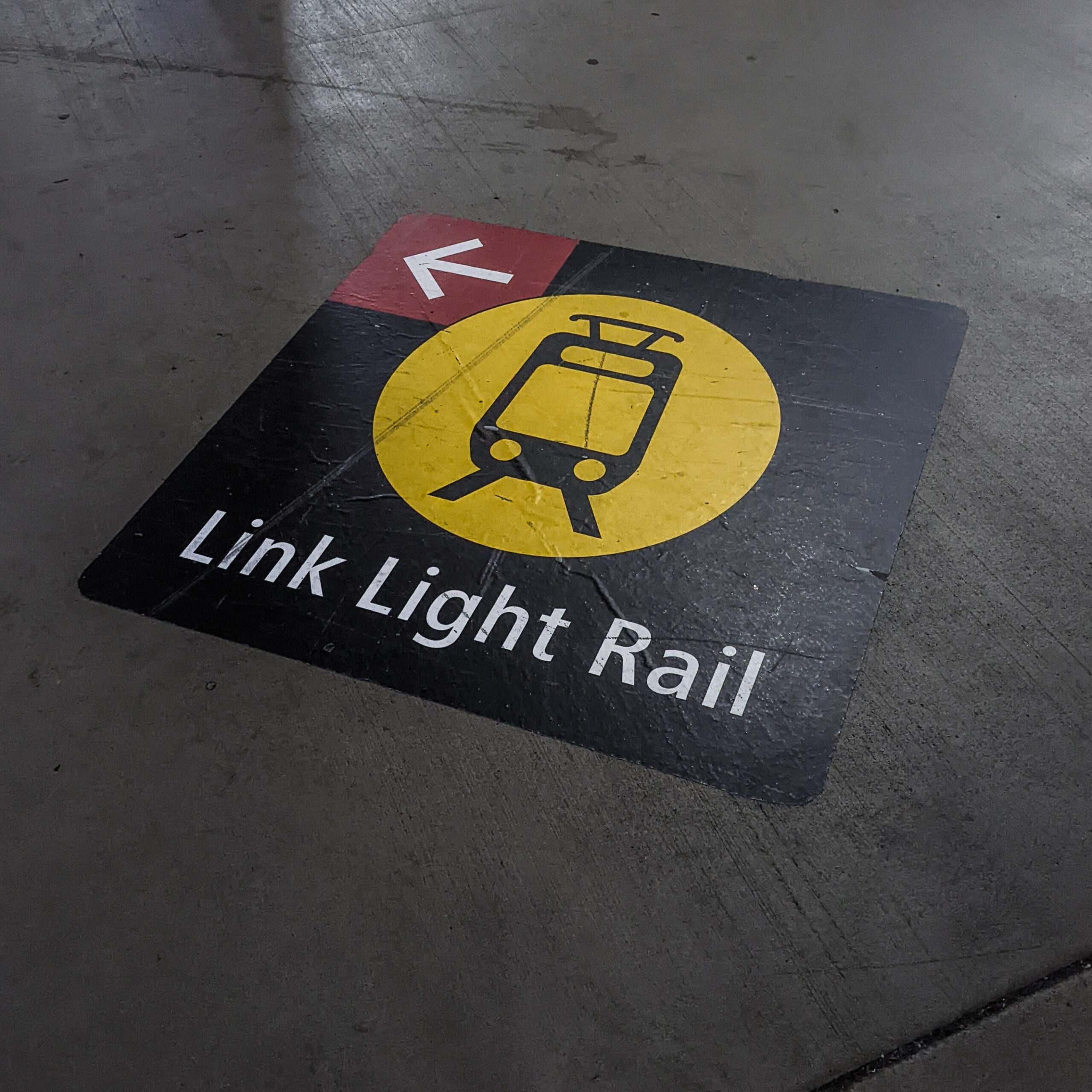 A sticker on the ground indicates what direction to follow to get to the light rail station