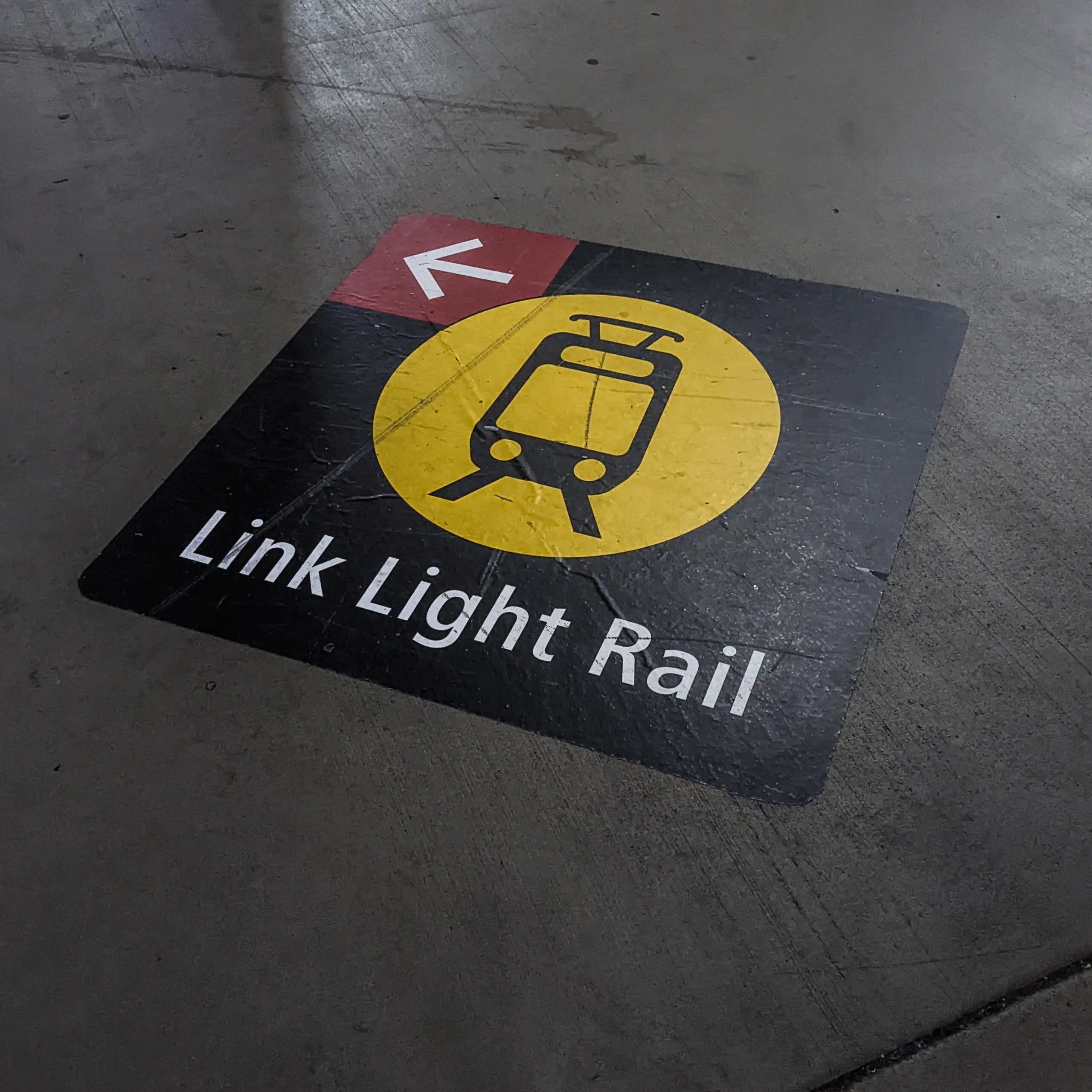 A sticker on the ground indicates what direction to follow to get to the light rail station